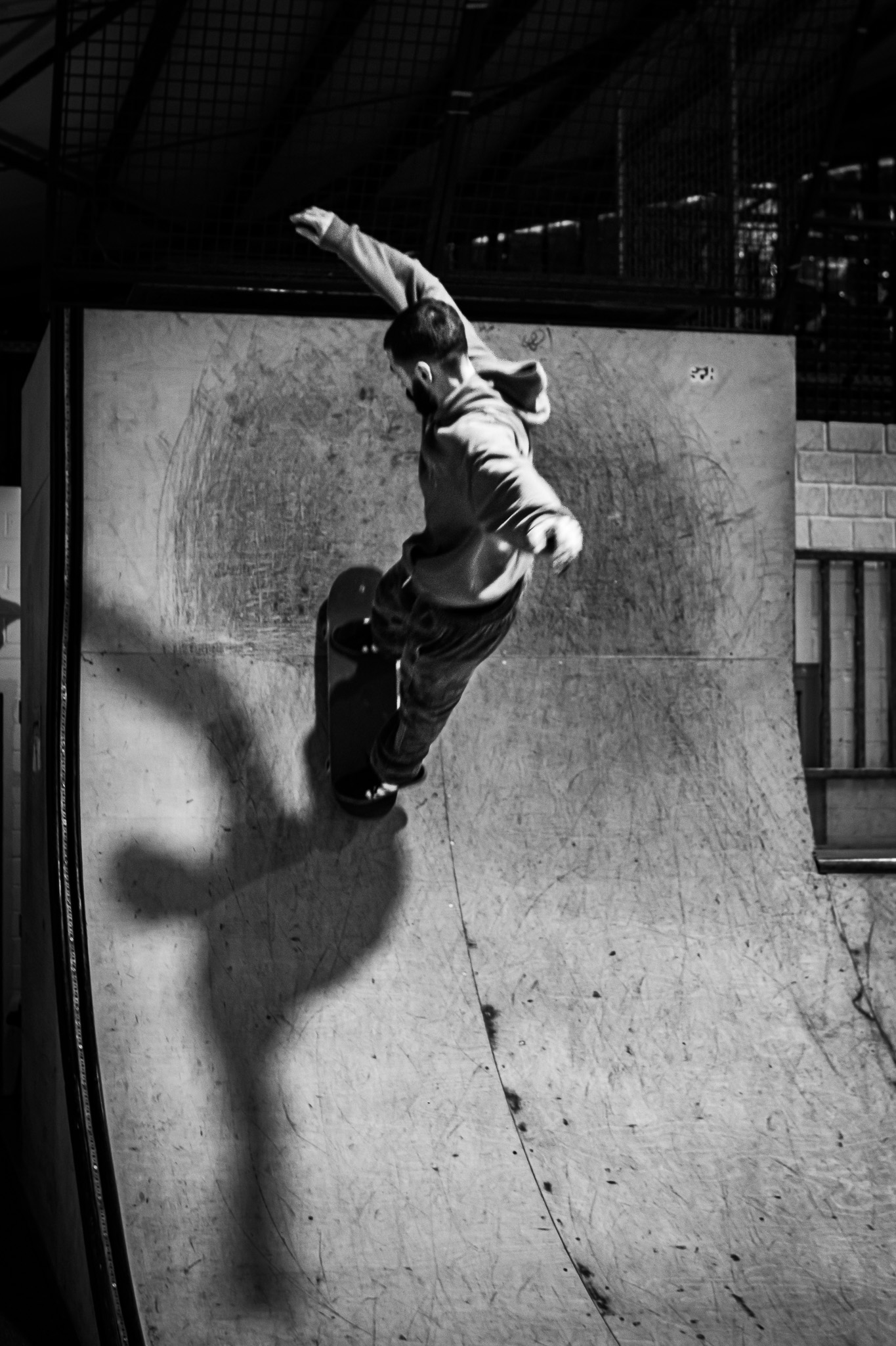 Skateboarder performing a trick on a vertical ramp in an indoor skatepark