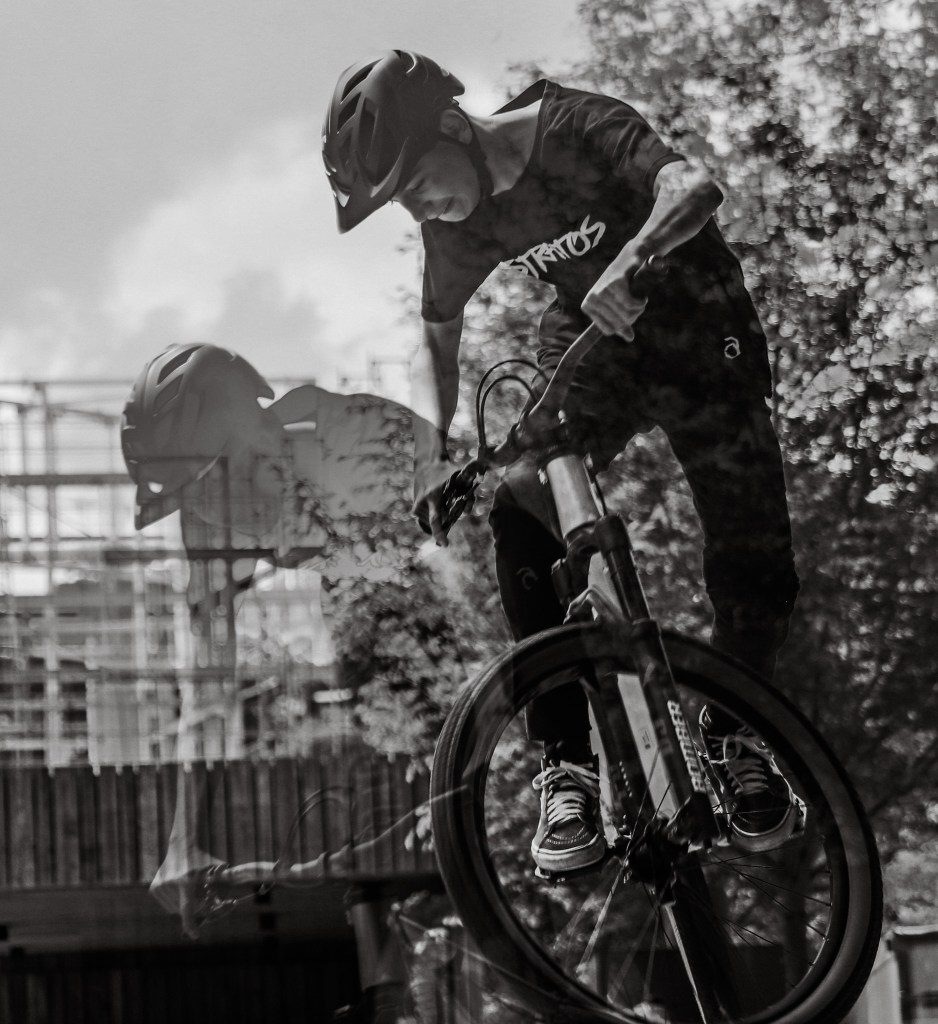 "A black and white image of a cyclist performing a jump on a BMX bike.