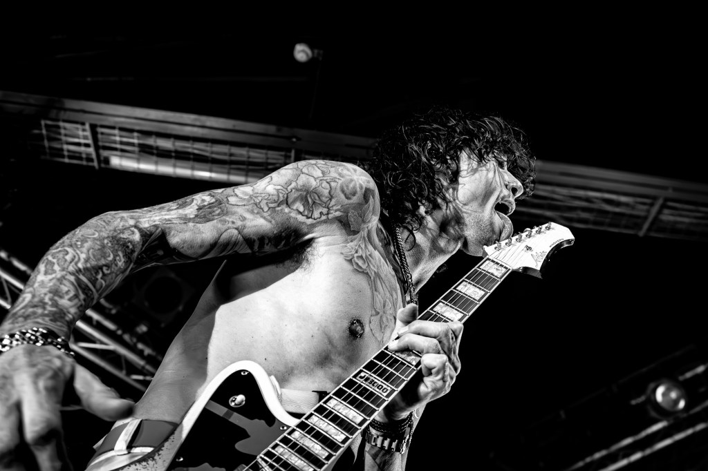 Justin Hawkins licking his guitar on stage