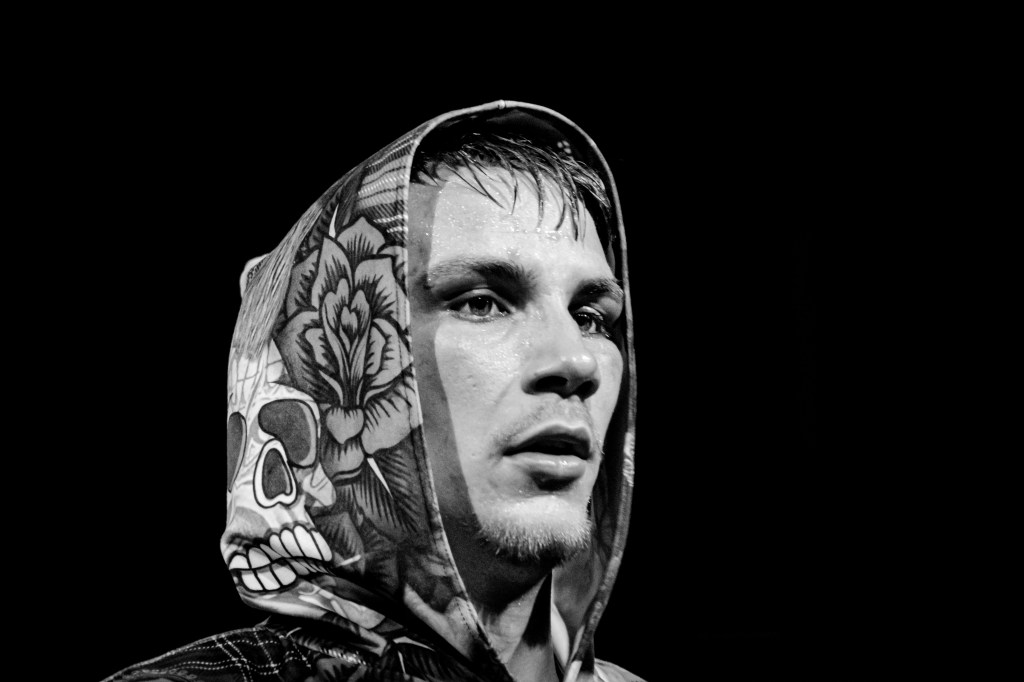 Black and white portrait of a male boxer wearing a decorative hooded sweatshirt, displaying a focused expression.