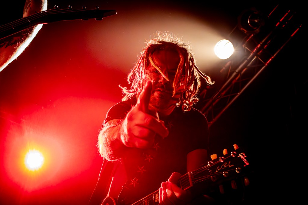 Mass Hysteria guitarist is looking and pointing finger at the camera ina. strong red light