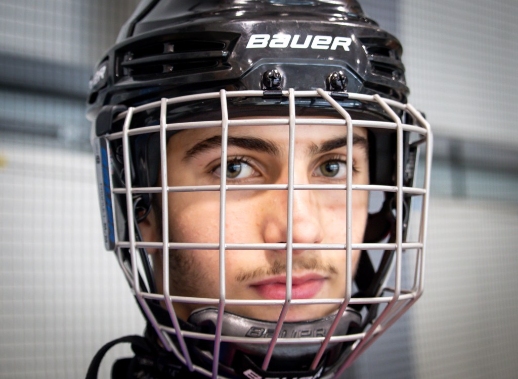 Close-up portrait of a young hockey player wearing a Bauer helmet and face cage.
