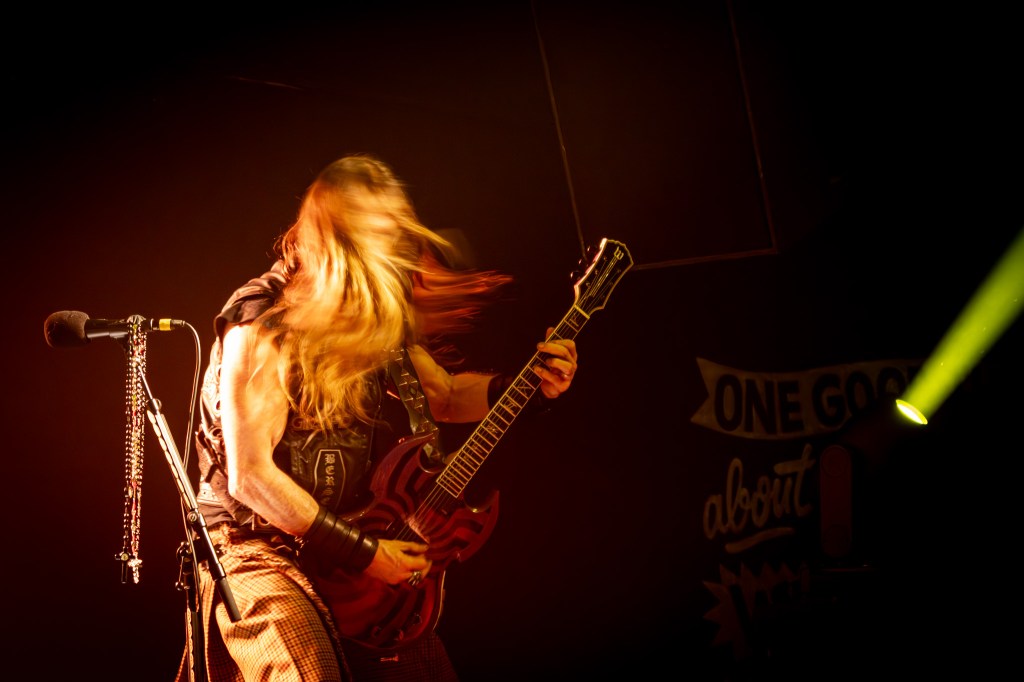 Guitarist Zakk Wylde in action during a live performance, passionately playing an electric guitar with long hair flowing