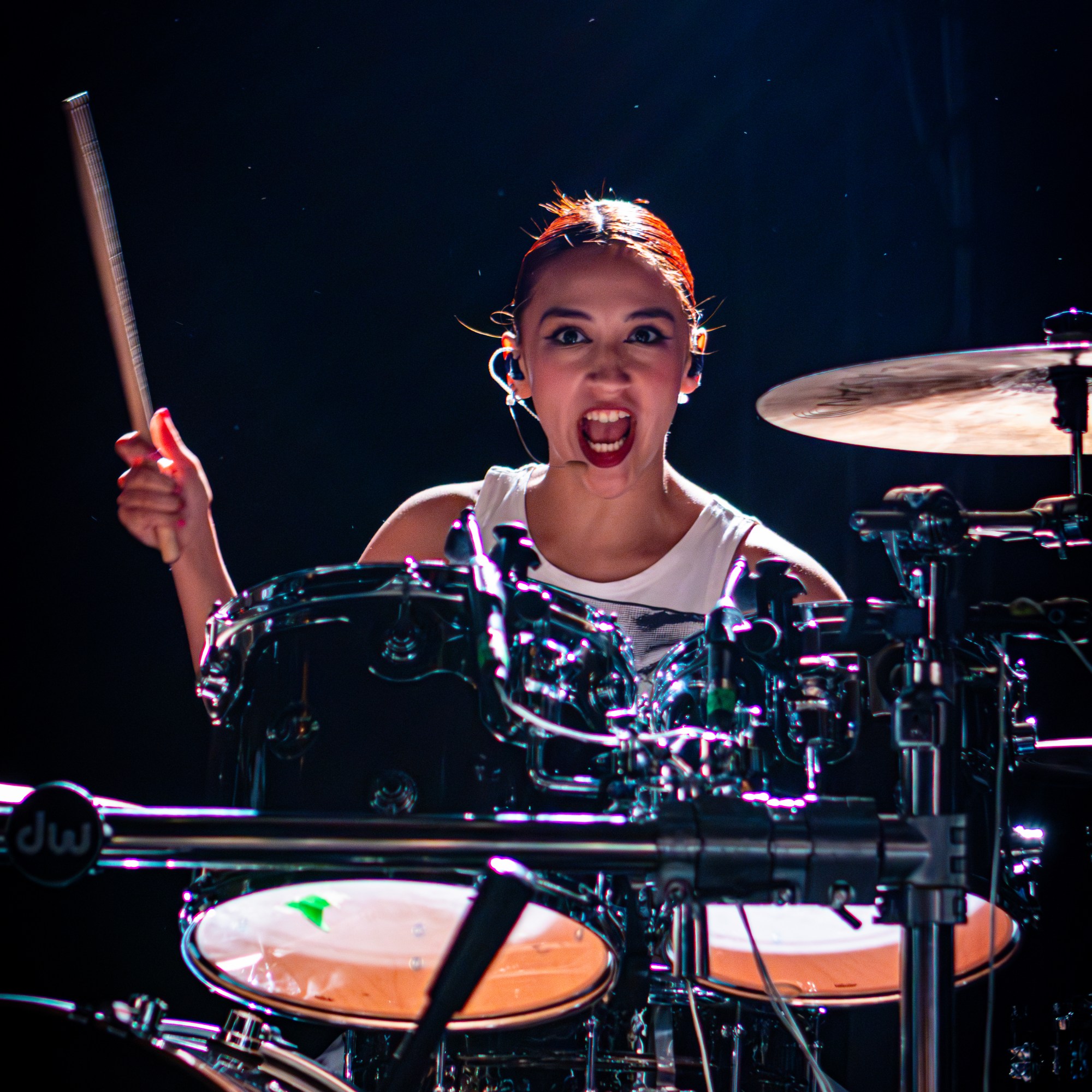 A drummer passionately performing on stage, captured mid-action with a fierce expression